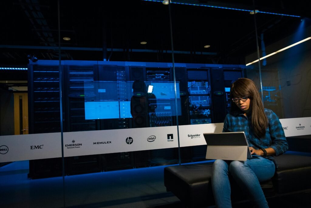 pexels-photo-1181320-1181320 Woman using a laptop in a server room, showcasing modern technology and work environment.